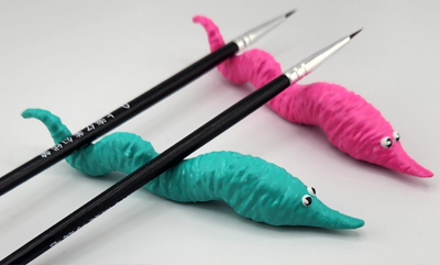 Two squiggle shaped worm brush rests one pink one blue