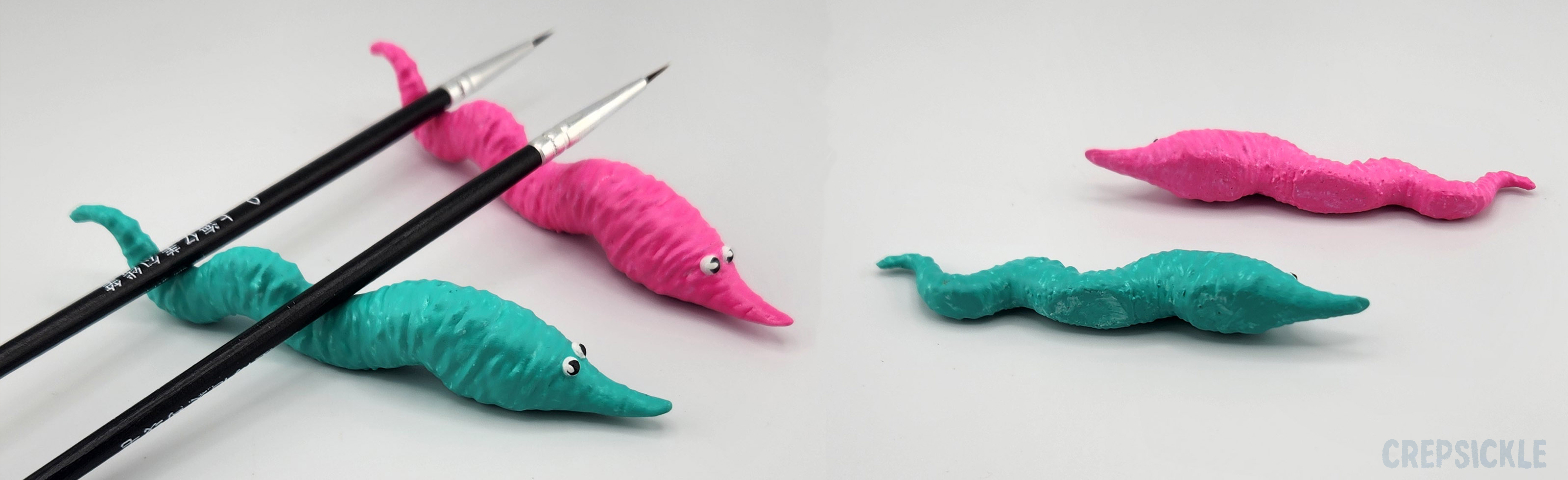 two brush rests, one painted like a pink and blue worm on string