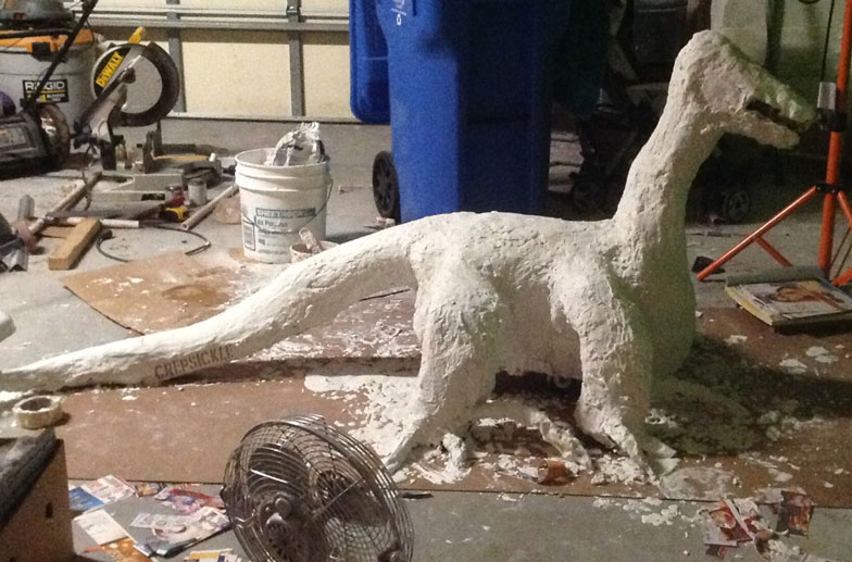 A large white paper mache lizard like creature