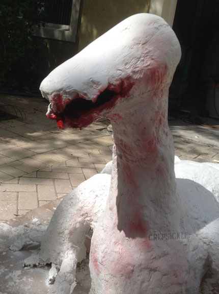 A large white paper mache lizard like creature