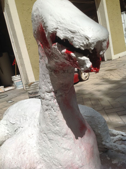A large white paper mache lizard like creature